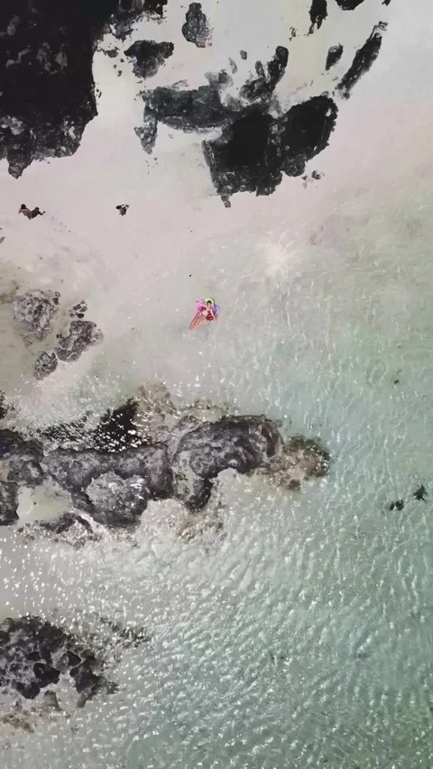 Top-down aerial view of a young woman in a bikini relaxing on a colorful 스톡 동영상 344838815