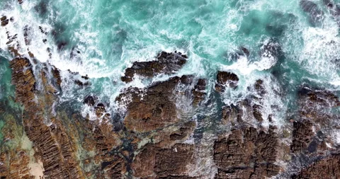 Top Down Aerial of Waves Crashing Over Rocky Coastline Stock Footage 330718224