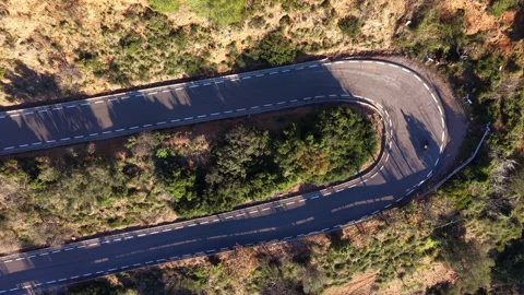 Top-down aerial of winding mountain road with evening shadows and geometry Video stock 326039540
