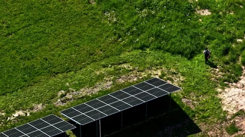 Top Down Aerial of Worker Mowing Grass Beside Solar Panels 스톡 동영상 333795211