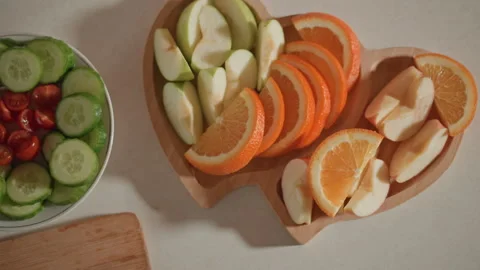 Top-down arrangement of sliced cucumber, cherry tomatoes, pear and orange in Stock Footage 346655247