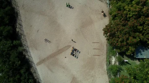 Top down ascending shot of equestrian center with stables and riders on Stock Footage 315479953