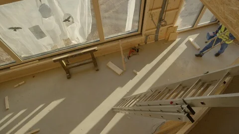 TOP DOWN: Builder leaves the construction site with toolbox and ladder in hand. Stock Footage 125040874