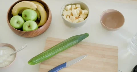 Top-down camera panning right, revealing cucumber on kitchen cutting board with Stock-Footage 344645617