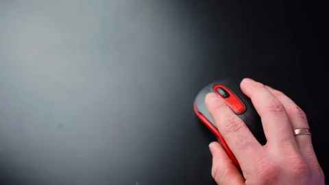 Top-down close-up of a hand resting on a black and red wireless mouse on a 스톡 동영상 331322488