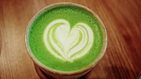 Top down close up of a matcha latte served in a ceramic cup on a wooden table Stock Footage 335343457