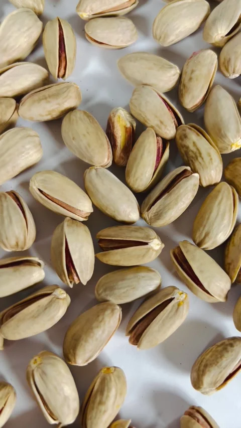 Top-down close-up pan shot from right to left of roasted pistachios Vídeos de archivo 336136143