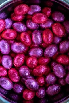 A top down close up portrait of a bunch of colorful chocolate easter eggs wra Stock Photos