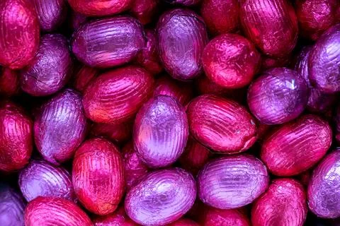 A top down close up portrait of a bunch of colorful chocolate easter eggs wra Stock Photos