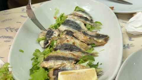 Top down close-up shot capturing a person eating grilled sardines with lemon Stock Footage 340155044