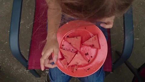 Top Down Close Up Shot of Child Holding Fresh Watermelon Slice Over Red Plate Stock Footage 345309967