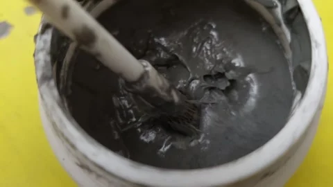 Top down close-up of a small paint brush stirring a thick grey liquid paste or g Stock Footage 336484565