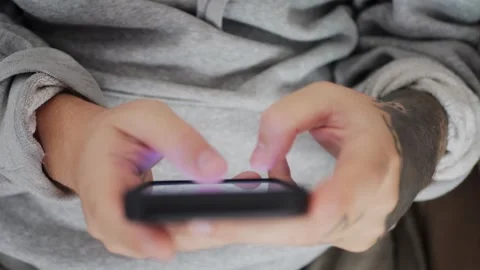 Top-down close-up of tattooed hands typing and texting on a smartphone... Stock Footage 318177983