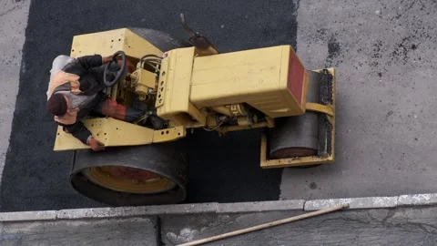 Top down close up view of a yellow road roller compacting new black asphalt.. 스톡 동영상 339802196