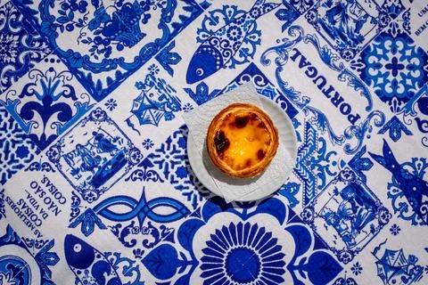 Top down closeup of single pastel de nata custard tart on traditional tablecloth Фото