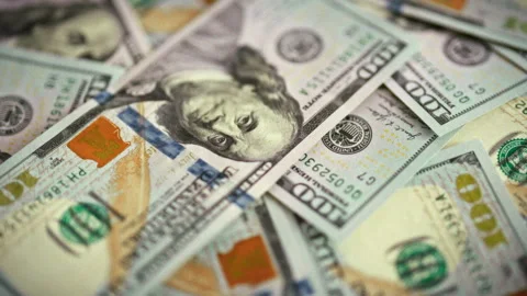 A top-down daylight shot captures fresh hundred-dollar bills fanned across a Stock Footage 336570317