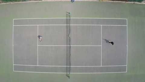 Top down drone aerial shot of couple playing tennis Stock Footage 128080645