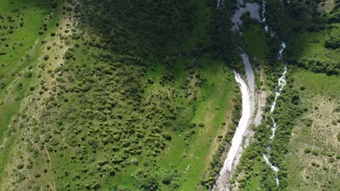 Top down drone camera tilts up to reveal lush green mountain valley, Kazakhstan Видео 337163983