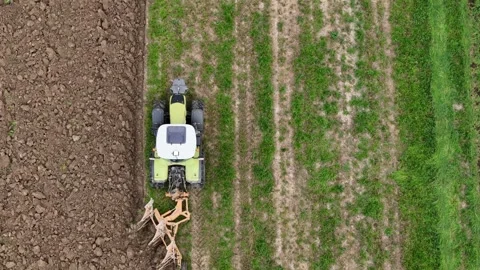 Top down drone close up shows a tractor with plow turning green field into .. Stock Footage 311763633