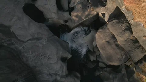 Top-down drone descent above quartzite waterfall and giant potholes at Vale da Stock Footage 341516536