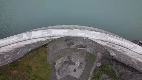 Top Down Drone Flight Across Curved Alpine Dam Toward Reservoir Stock Footage 336367470