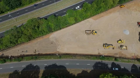 Top-down drone flyover of triangular construction site, diggers, roads Stock Footage 312369557