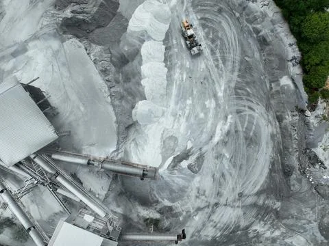 Top-down drone image of crushing plant and dust-covered trucks producing bu.. 스톡 사진