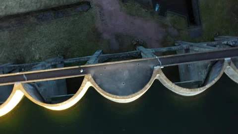 Top-down drone orbit over dam with woman walking, aerial rotation and ascend sho Stock-Footage 333177939