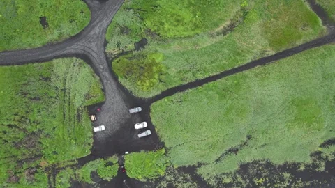 Top down drone rise over gravel parking lot and green fields near Vik, Iceland Stock Footage 346552414