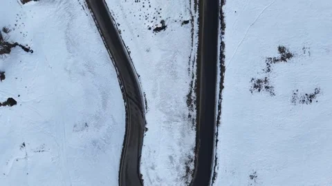 Top Down Drone Rising Over Snowy Mountain Road in Switzerland 스톡 동영상 329557800