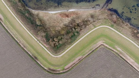 Top-down drone shot of bikers on a dike near Brouwershaven with farmland Video stock 305470424