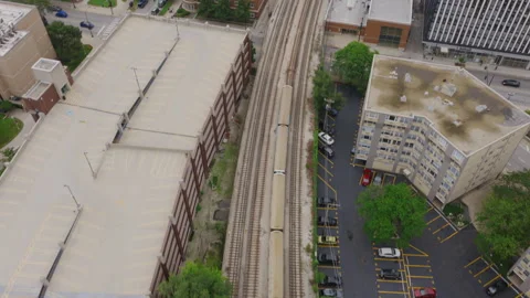 Top-down drone shot of a Chicago "L" train passing between tree-lined tracks Stock Footage 345874841