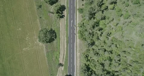 Top down drone shot of cyclists and cars on a rural street in South of France Stock Footage 196810167