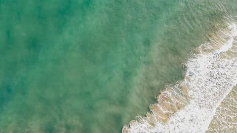 Top down drone shot of emerald green sea water and white foamy waves crashi.. Foto stock