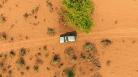 Top-down drone shot of a lone 4x4 following sandy tire ruts across orange Stock Footage 345846379