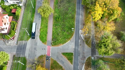 Top-down drone shot of a modern tram or bus crossing tram tracks at an Stock Footage 320382173