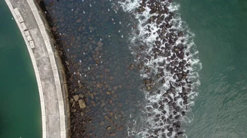 Top down drone shot of ocean waves crashing against a seawall coastal defence Stock Footage 208820317