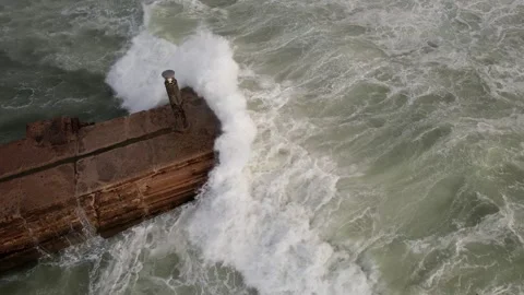 Top down drone shot of ocean waves crashing against a seawall Stock Footage 253344579
