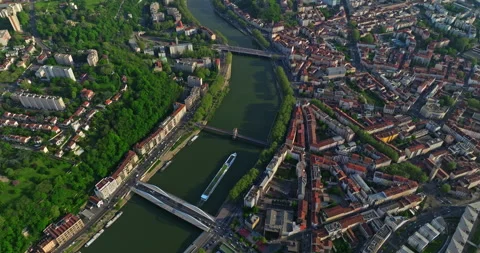 Top down drone shot over town at sunset along a blue river. A tourist ship moves 스톡 동영상 275199184