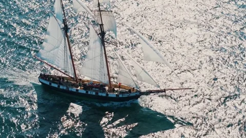 Top down drone shot of sailing ship on calm sea with sunset reflection on water Stock Footage 330921260