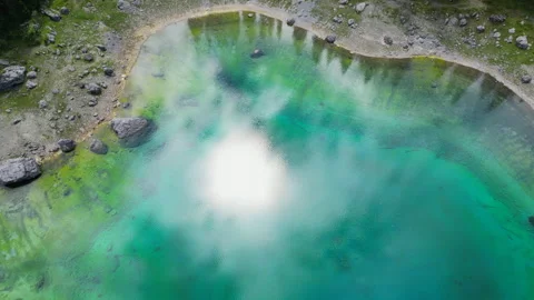 Top down drone shot of the stunning alpine Lake Carezza. Ethereal fog is gently 库存影片 334838586