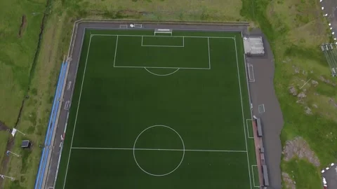 Top-down drone shot tilting up to reveal football field by ocean, Faroe Islands. Stock Footage 340168763