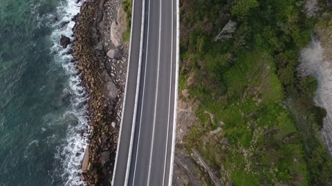 Top down drone shot view of a bridge at the ocean with waves and hills Stock Footage 143620491