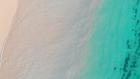Top down drone shot of waves rolling on shore. Stockbeeldmateriaal 99577012
