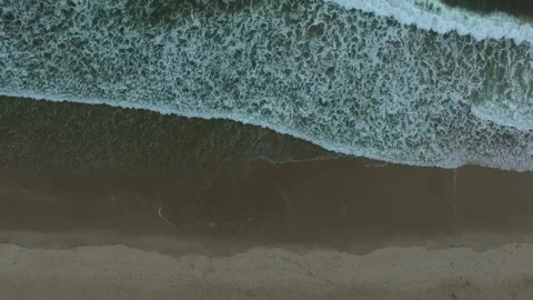 Top down drone shot of waves crashing on shore gaining elevation Stock Footage 232917675
