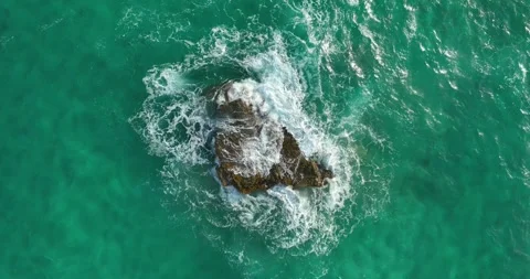 Top down drone shot of waves breaking over a rock Stock Footage 343622259