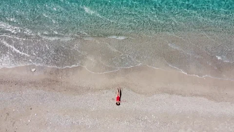 Top down drone shot, young woman lying on her back on white sand tropical beach  Stock Footage 165627230