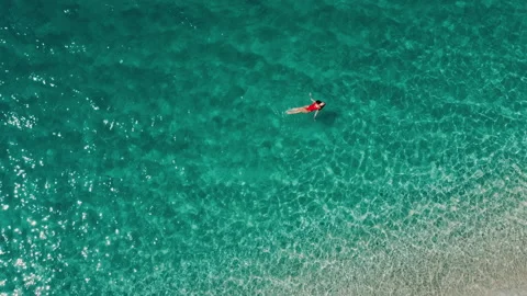 Top down drone shot, young woman lying on her back on white sand tropical beach  Stock Footage 165629491