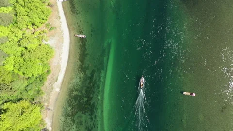 Top down drone tracking motorboat in clear emerald river water with shoreline an Video stock 333529455