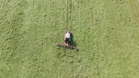 Top down drone video of a tractor mixing grass for dying before harvesting Stock Footage 312069996